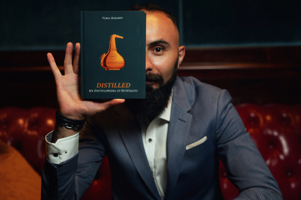 Tural Hasanov with his book Distilled: My Encyclopedia of Beverages