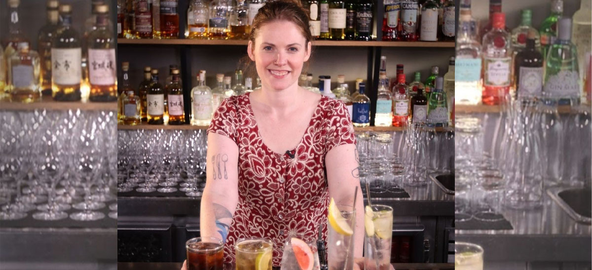 Wineglass stands on bar and woman bartender holds mixing cup and